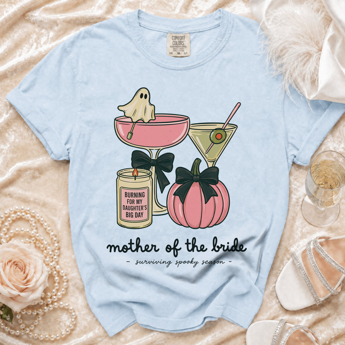 Light blue t-shirt with graphic of ghost in martini glass, pumpkin, and candle reading "Mother of the Bride".