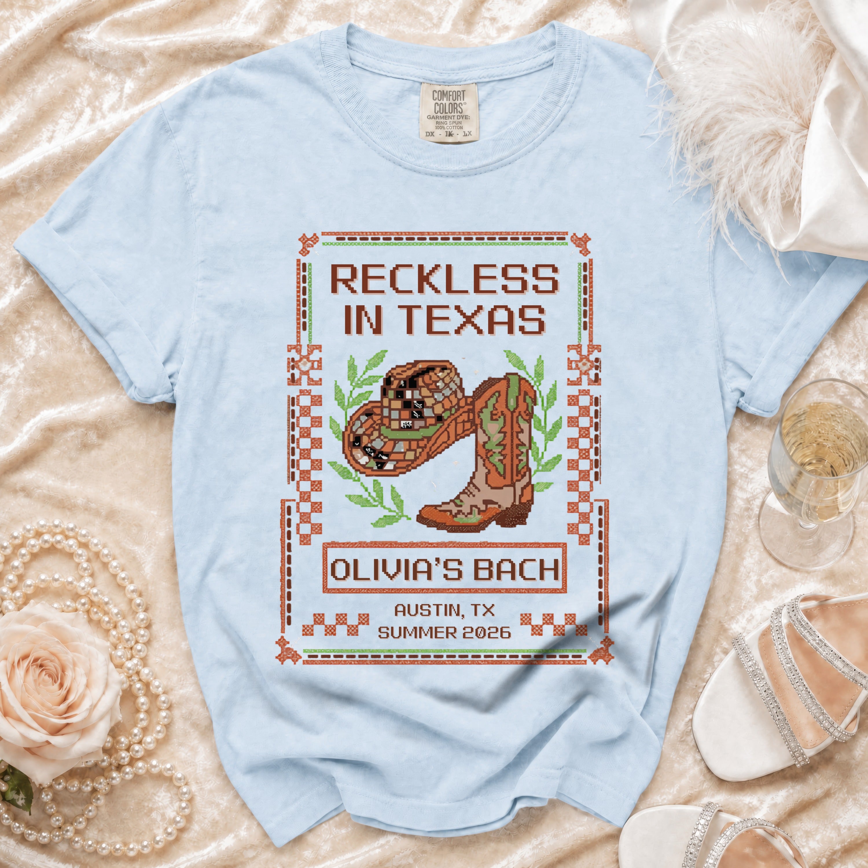Light blue t-shirt with "Reckless in Texas Olivia's Bach Austin, TX Summer 2026" design.