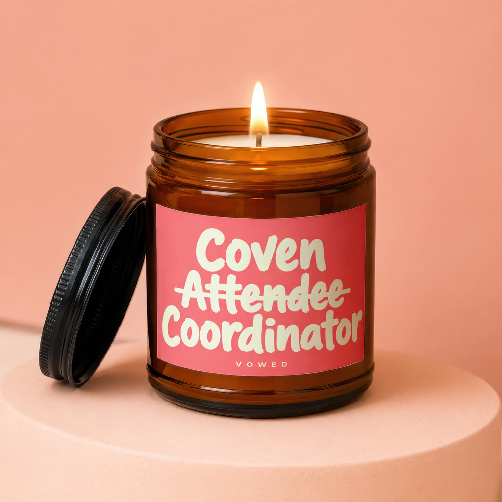 Amber jar candle with lid off, lit flame, and "Coven Attendee Coordinator" label.