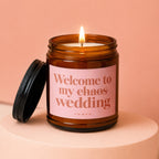 Candle in amber glass jar with pink label reading "Welcome to my chaos wedding".
