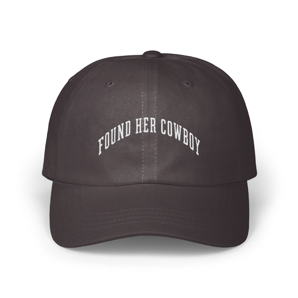 A dark grey baseball cap featuring white embroidered text that reads FOUND HER COWBOY.