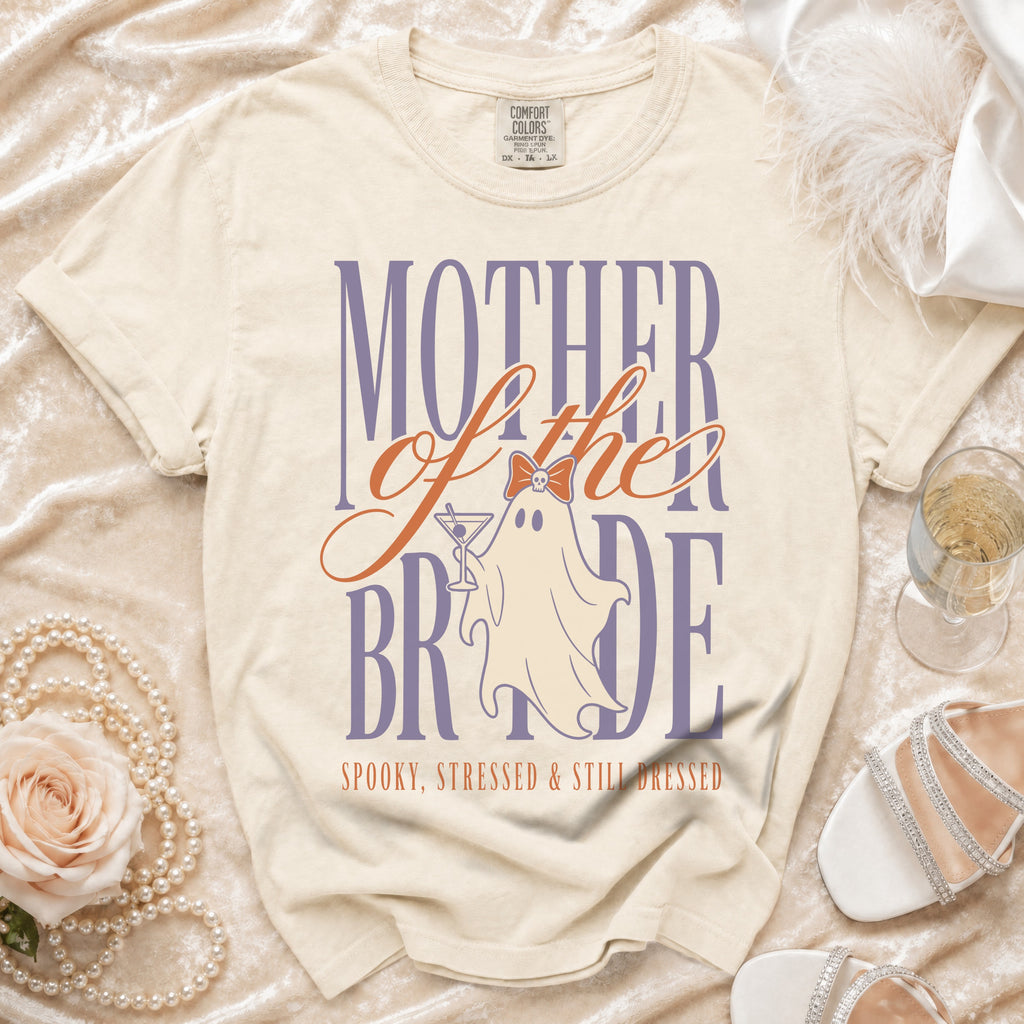 Cream t-shirt with "Mother of the Bride" ghost graphic and "Spooky, Stressed & Still Dressed" text.