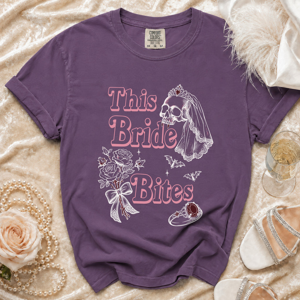 Purple t-shirt with "This Bride Bites" text, skull bride graphic, bouquet, and ring.