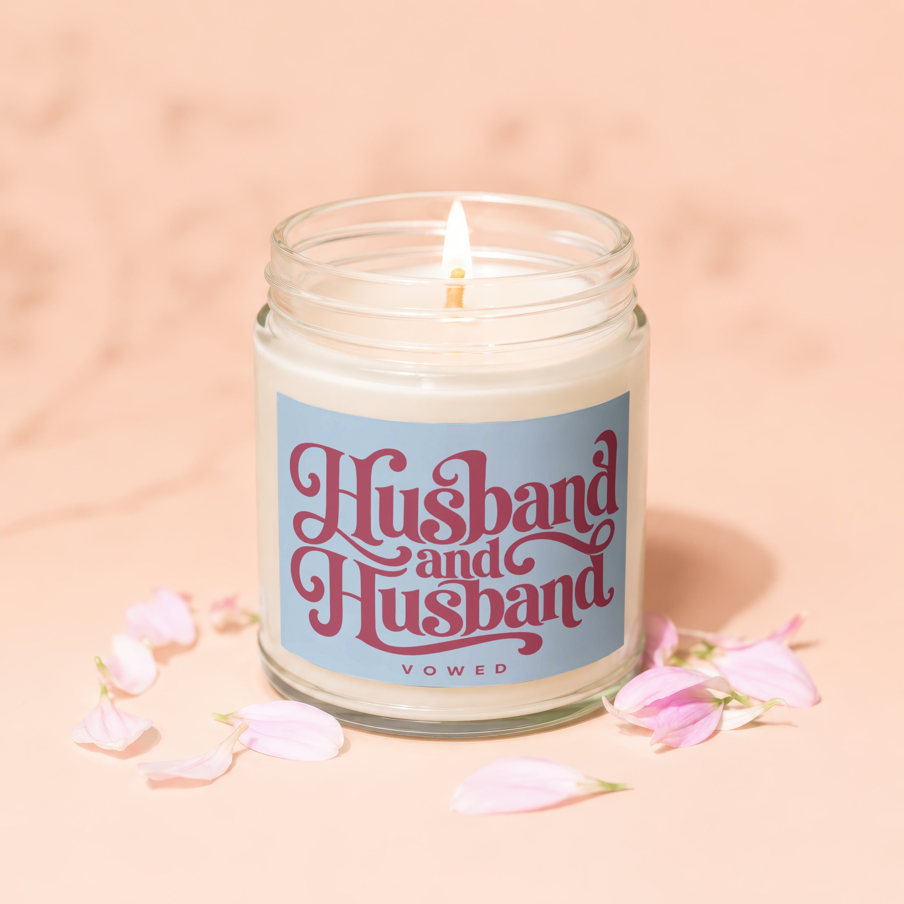 Candle with "Husband and Husband Vowed" text on label, surrounded by petals.