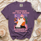 Purple Comfort Colors t-shirt with "Mother of the Bride Scared of Nothing" graphic.