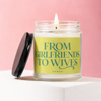 Glass jar candle with lit flame and black lid. Text reads "FROM GIRLFRIENDS TO WIVES"