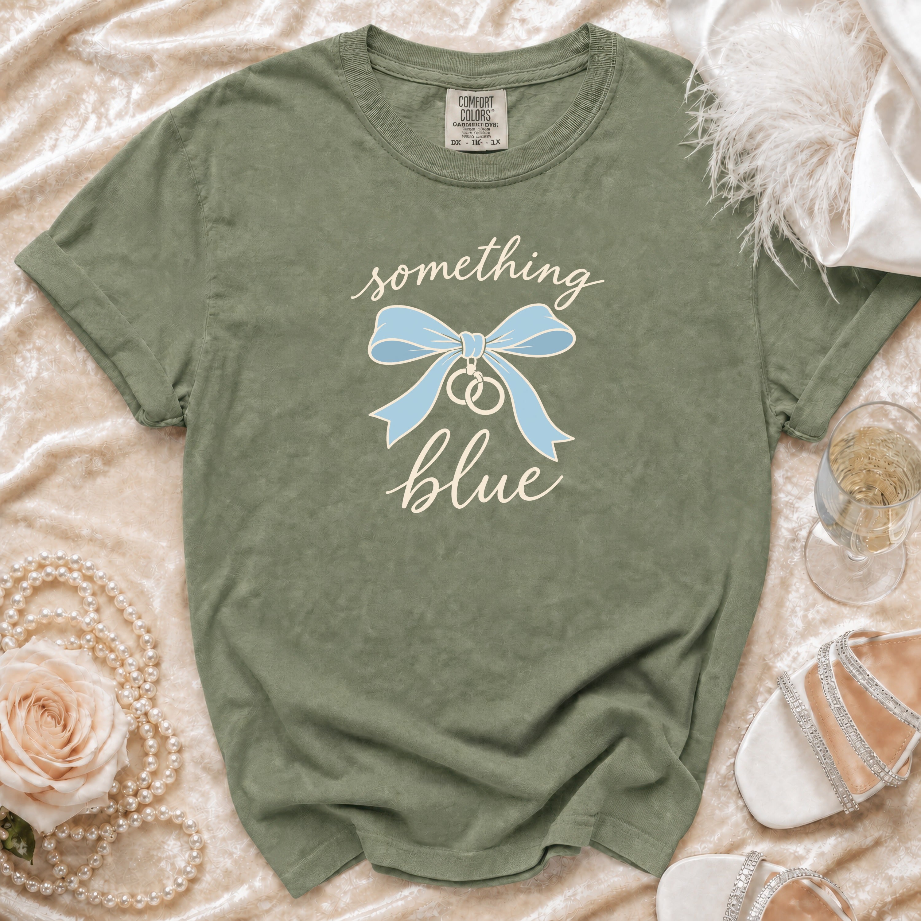 Olive green t-shirt with "something blue" text, blue bow, and wedding rings graphic.