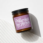 Amber jar candle with black lid, pink label reads "Married my person" and "VOWED".