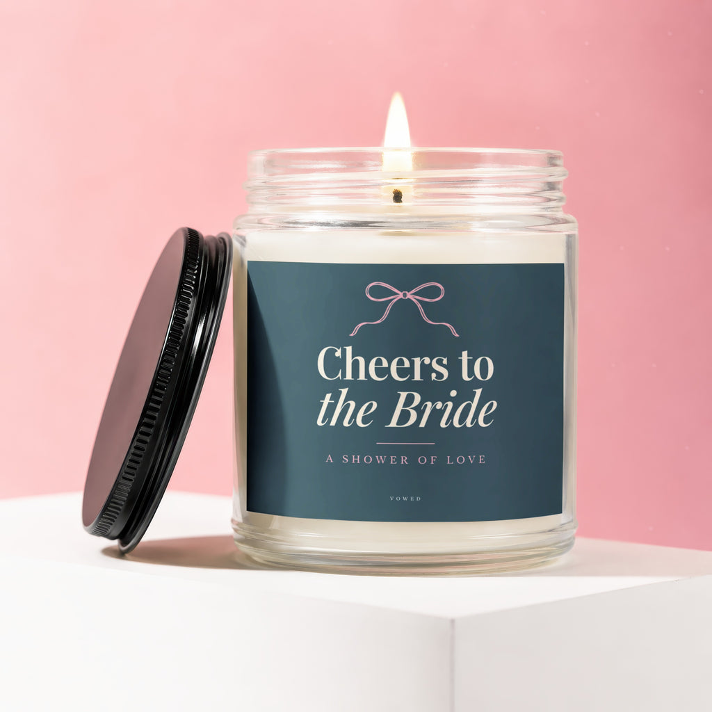Candle with lit wick and "Cheers to the Bride" text on a dark blue label.
