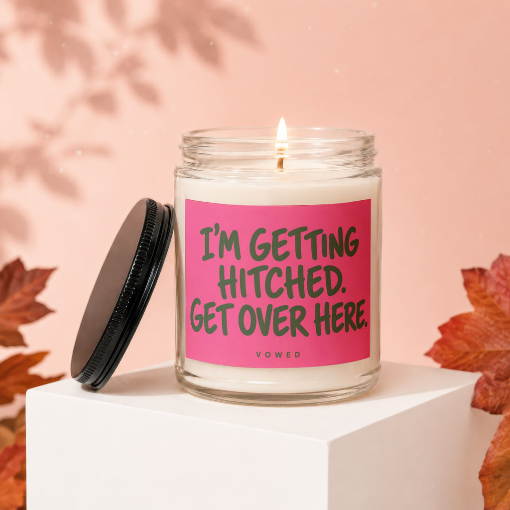 Jar candle with lit wick and black lid, reading "I'M GETTING HITCHED. GET OVER HERE. VOWED."