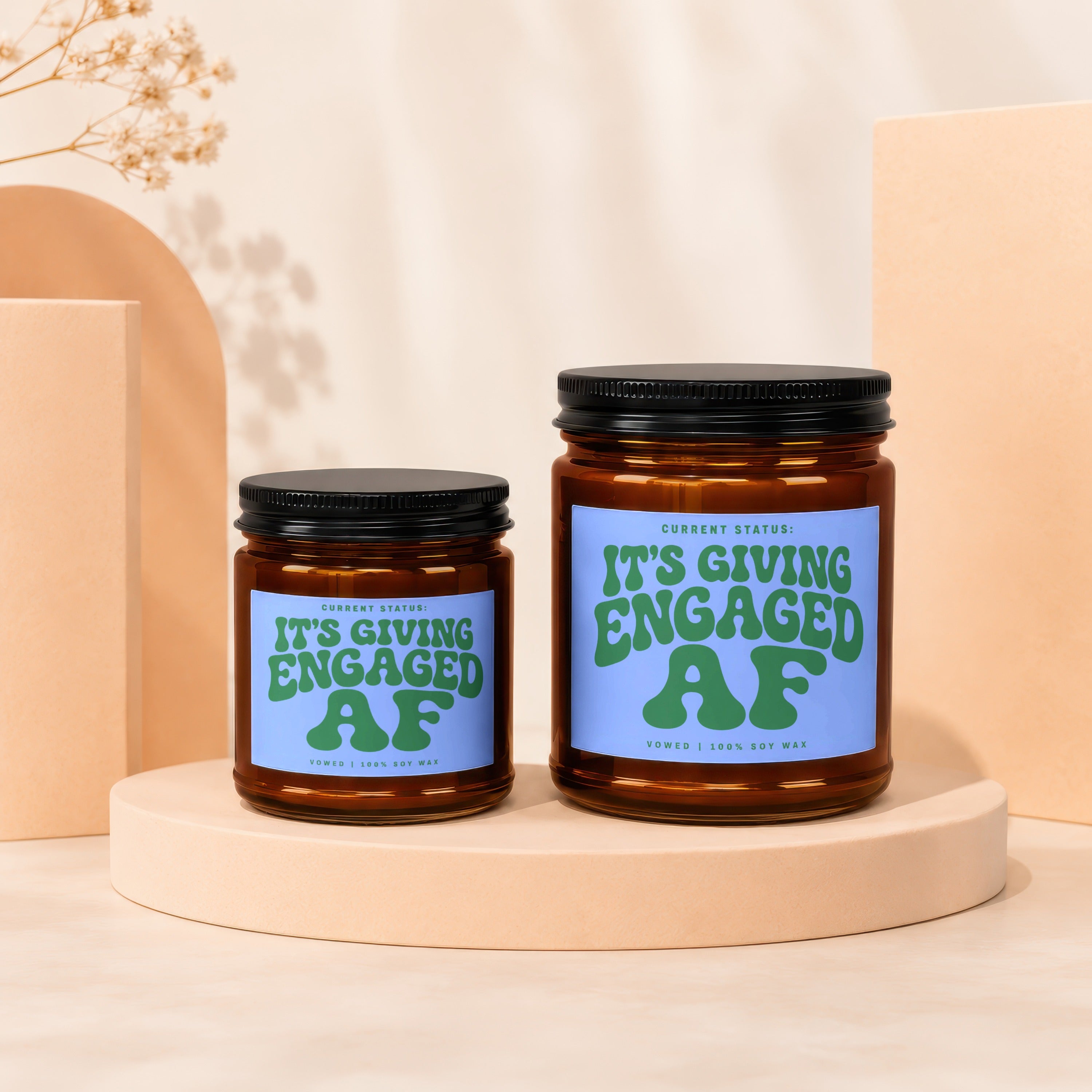 Two amber glass candles with blue labels reading "It's Giving Engaged AF".