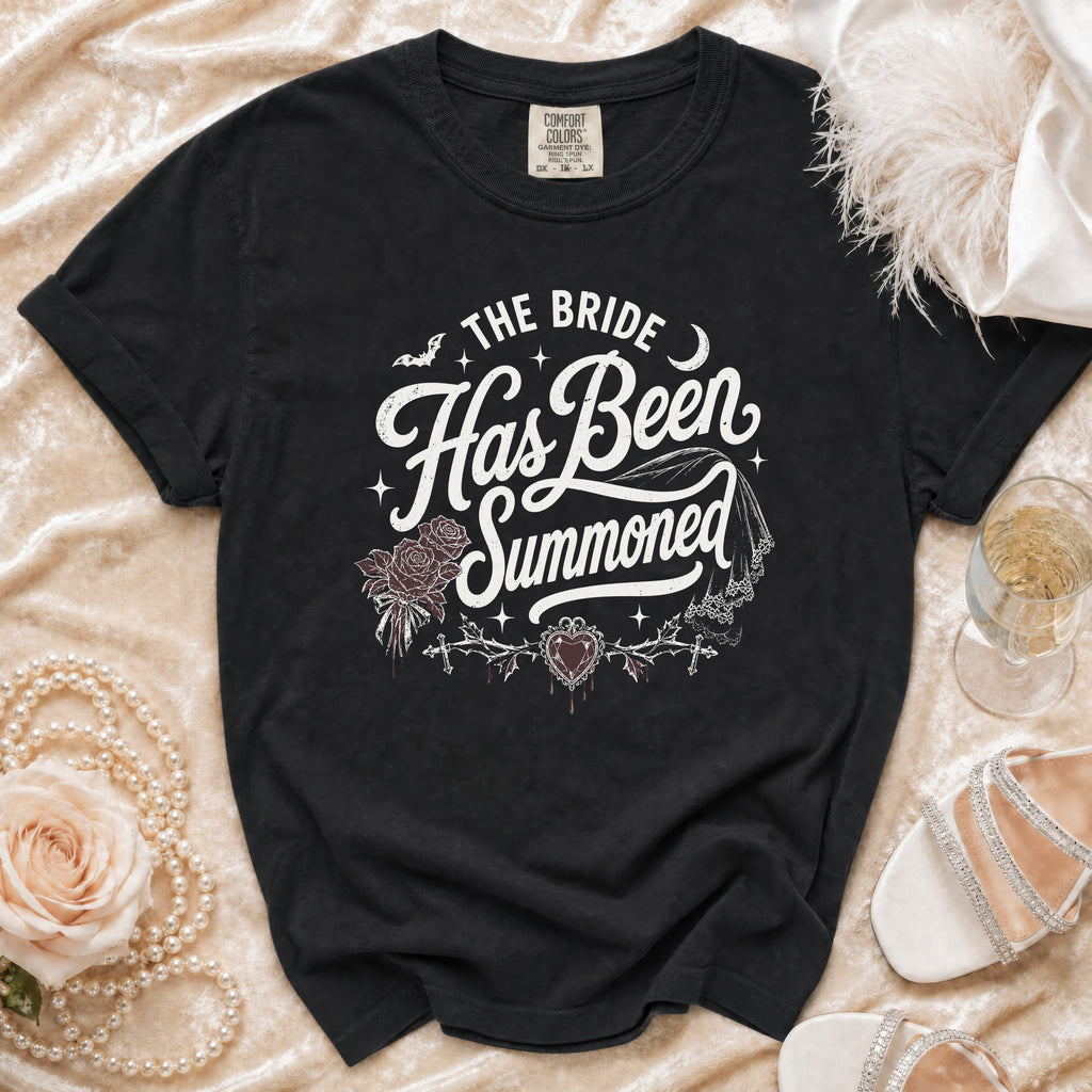 Black t-shirt with white gothic text "The Bride Has Been Summoned" and wedding motifs.
