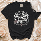 Black t-shirt with white gothic text "The Bride Has Been Summoned" and wedding motifs.