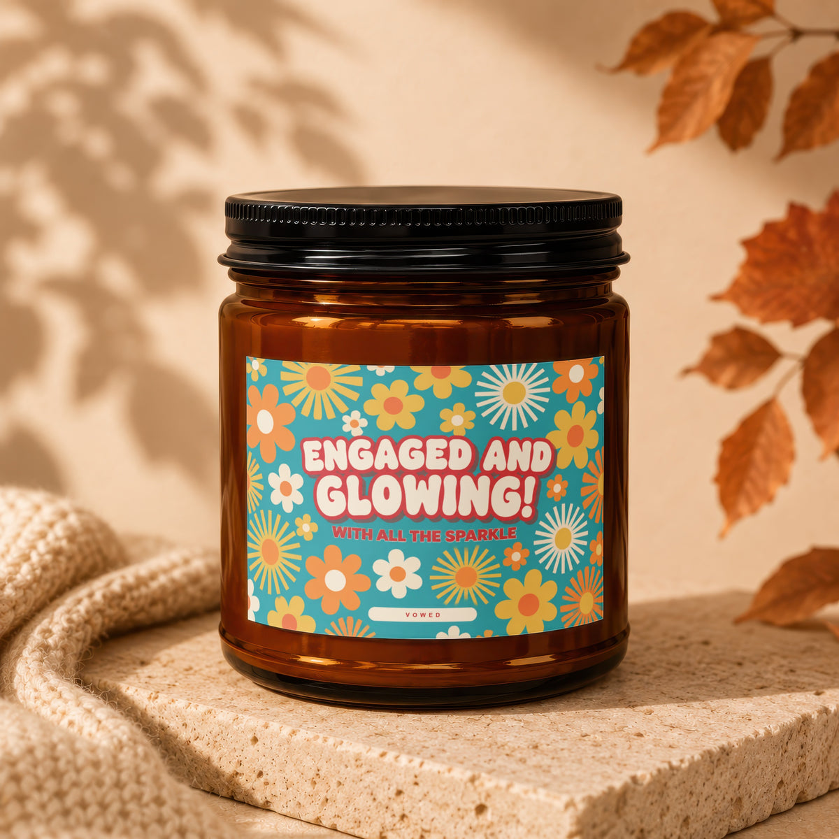 Brown glass candle with "Engaged and Glowing!" text and floral pattern label.
