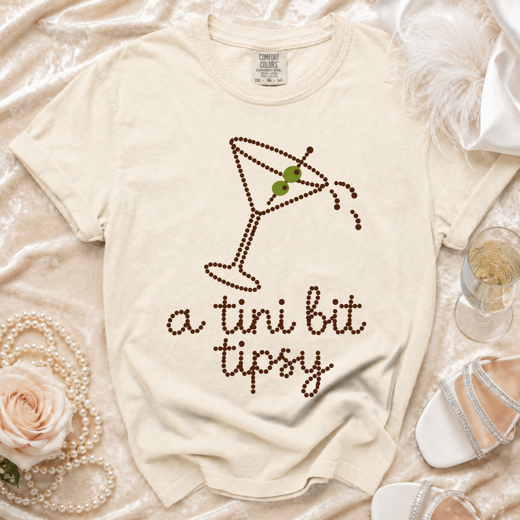 Cream t-shirt with martini glass design and "a tini bit tipsy" text.