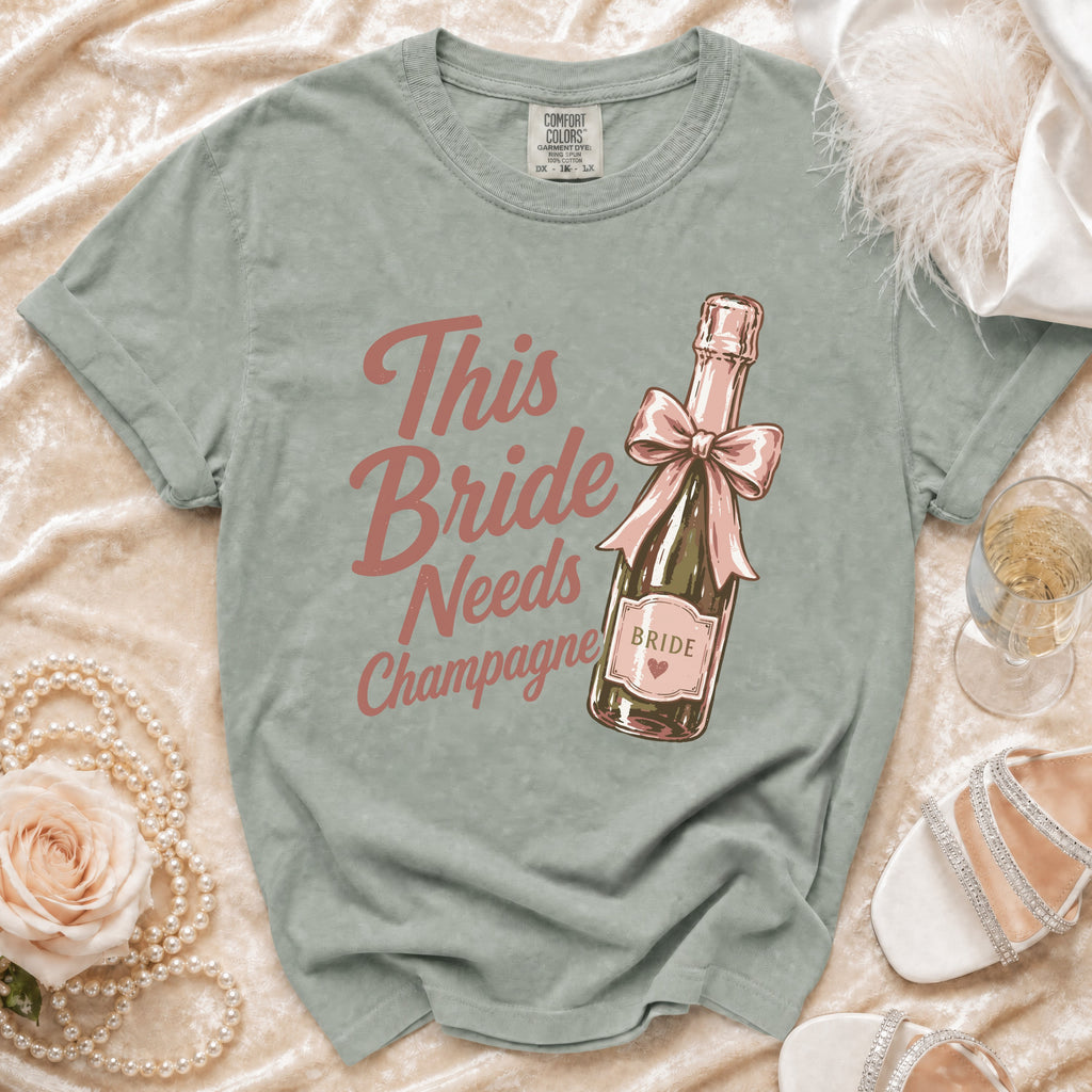 Green t-shirt with "This Bride Needs Champagne" text over a champagne bottle graphic.