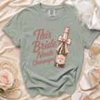 Green t-shirt with "This Bride Needs Champagne" text over a champagne bottle graphic.