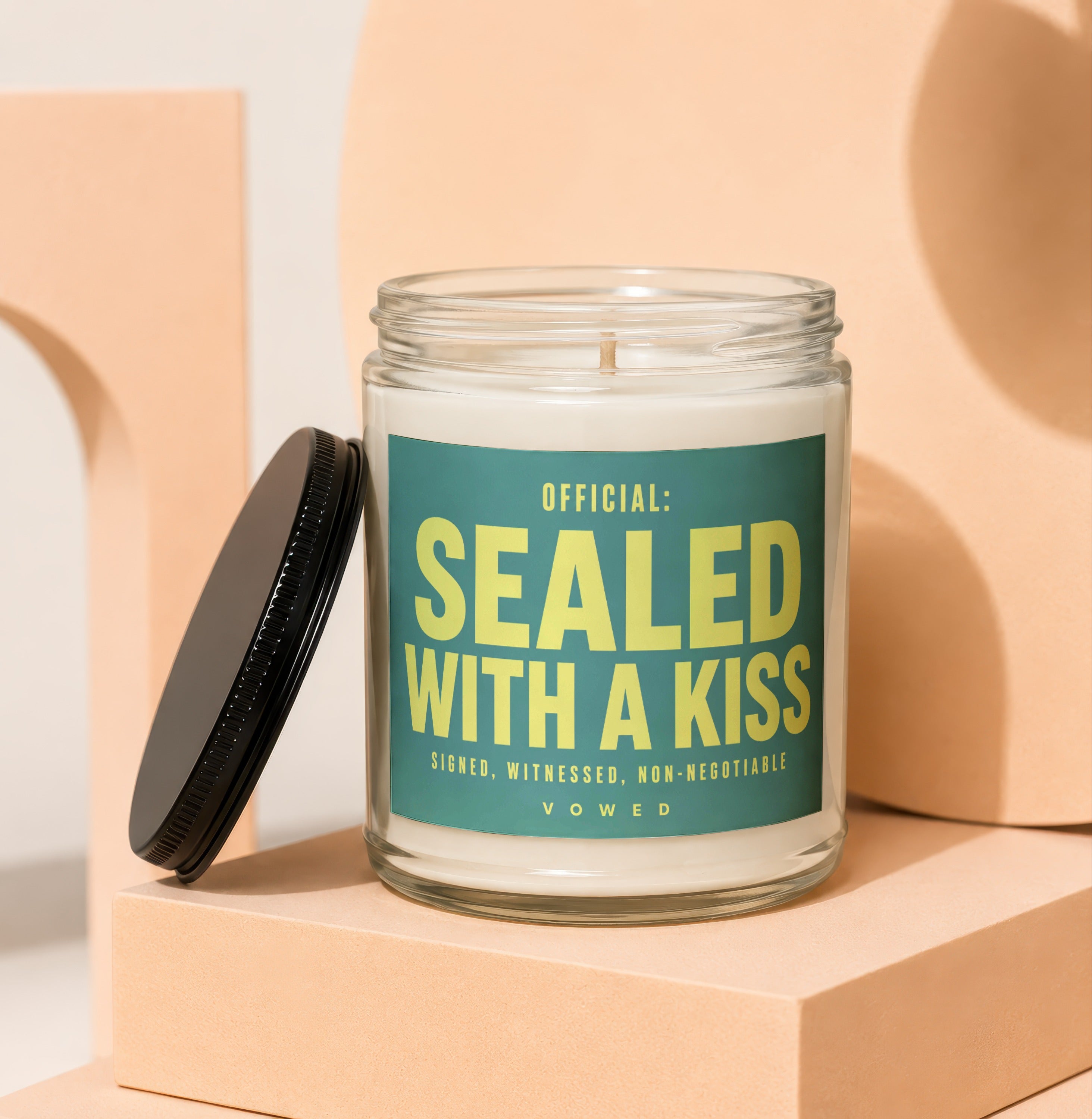 Glass candle with green label reading "OFFICIAL: SEALED WITH A KISS"