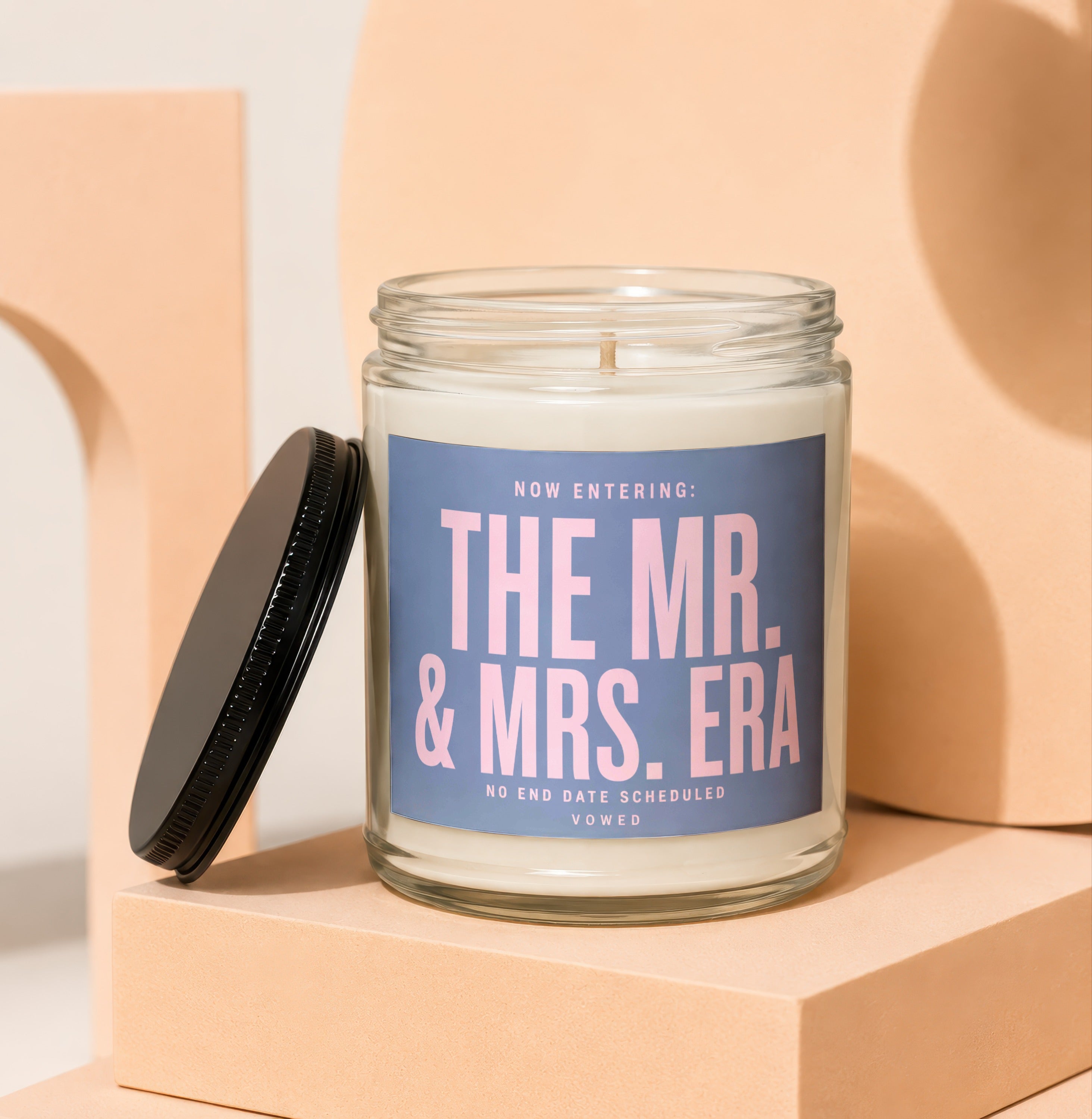 Candle with "The Mr. & Mrs. Era" text and a black lid.