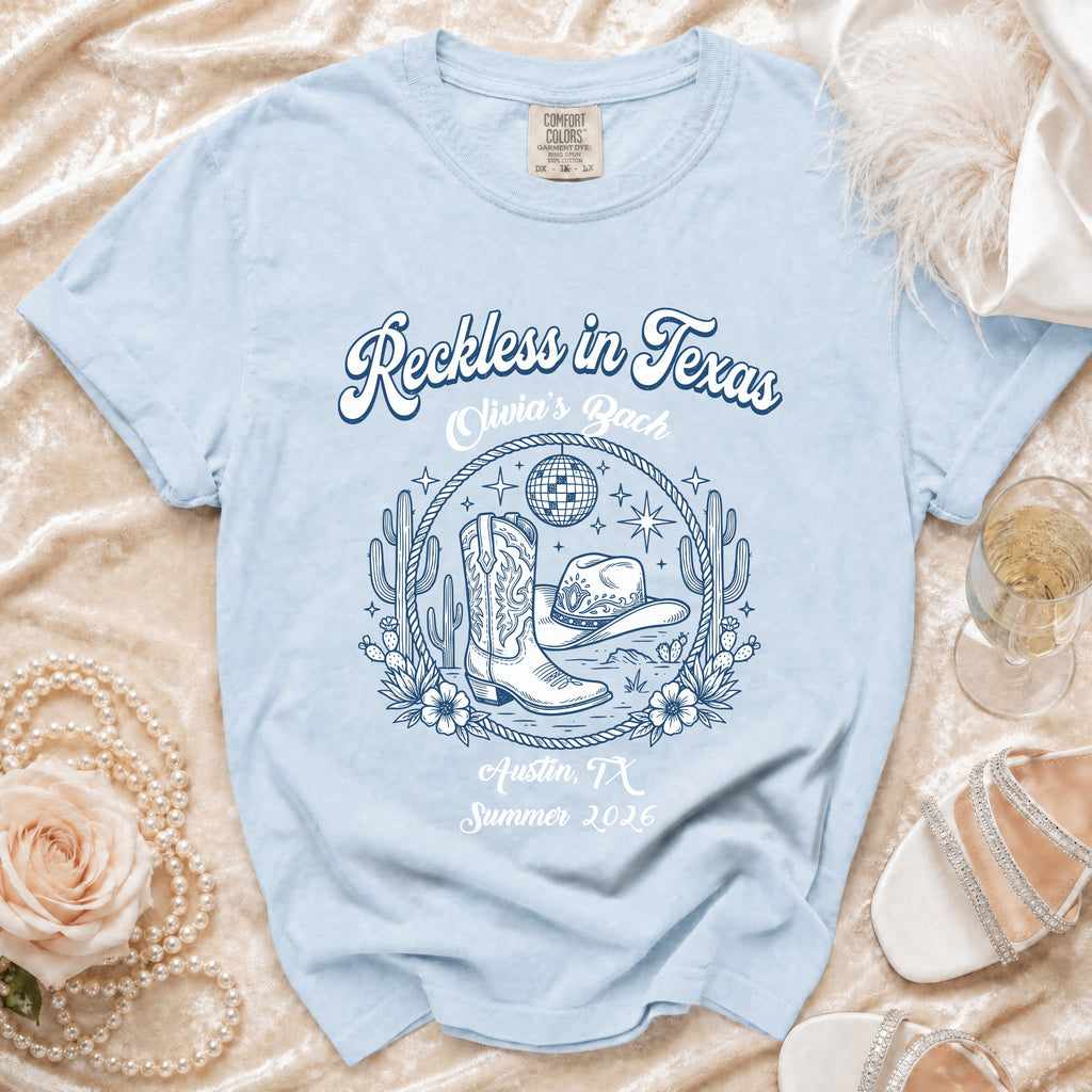 Light blue t-shirt with "Reckless in Texas" and Austin, TX Summer 2026 graphic.