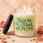 Jar candle with text "Kept the U-Haul, got the ring" on a light green label.