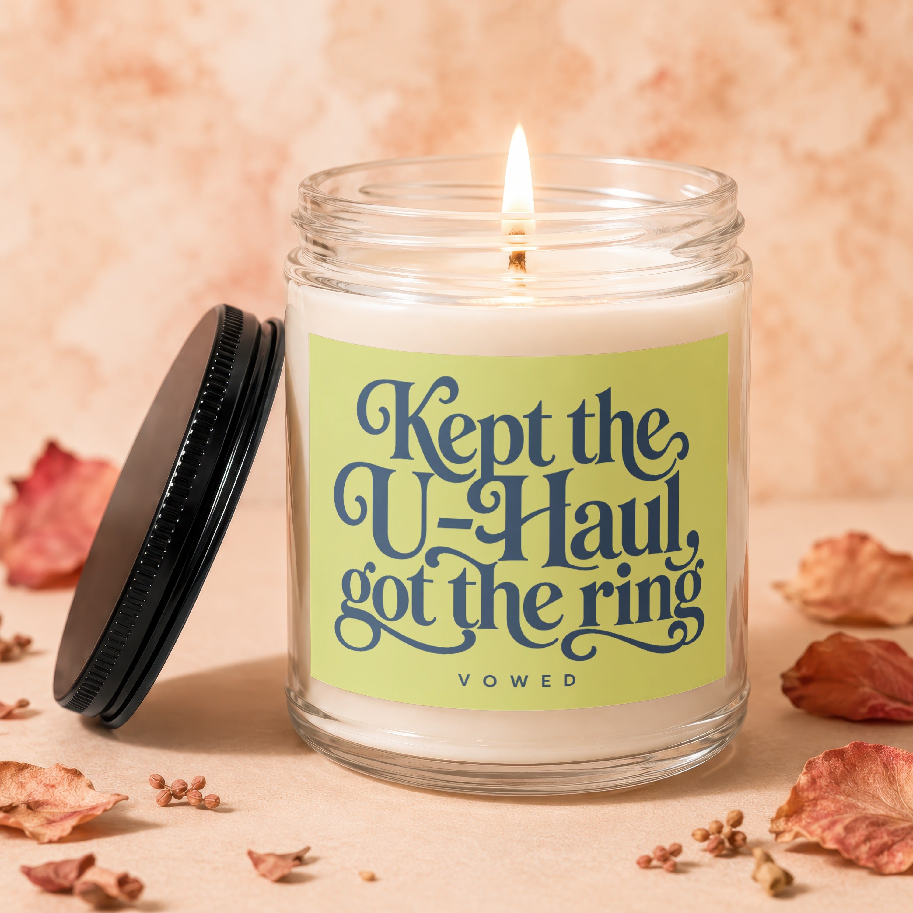 Jar candle with text "Kept the U-Haul, got the ring" on a light green label.