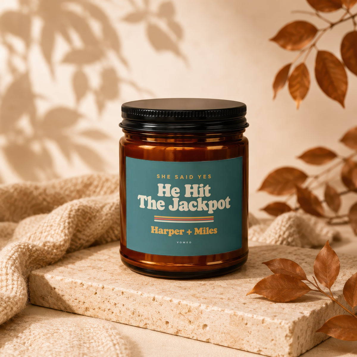 Amber candle with black lid labeled "He Hit The Jackpot" and "Harper + Miles".
