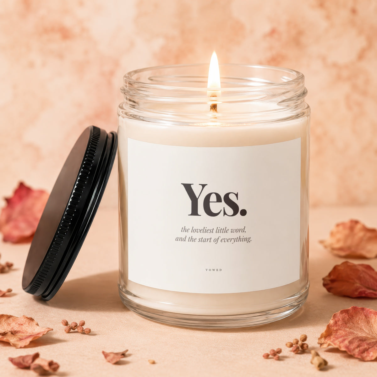 A lit candle in a glass jar with the text "Yes." and "the loveliest little word, and the start of everything."