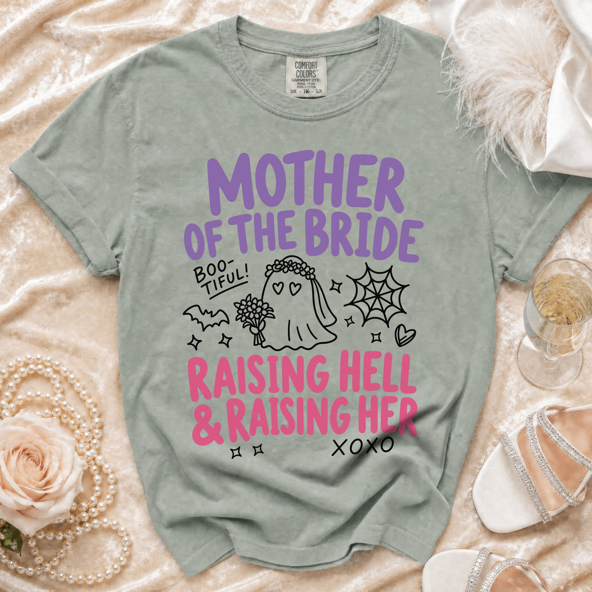 Green t-shirt with "Mother of the Bride" graphic and "Raising Hell & Raising Her" text.
