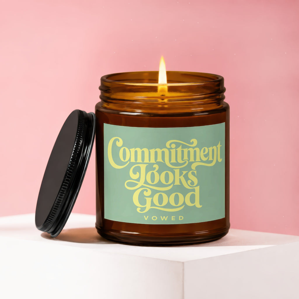 Amber jar candle with lit flame reads "Commitment Looks Good" and "VOWED".