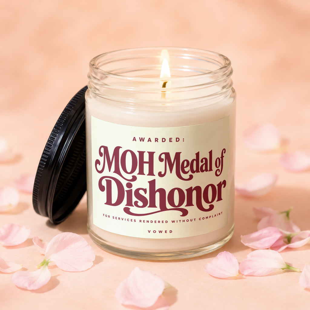 Candle with "MOH Medal of Dishonor" text, lid off, surrounded by pink petals.