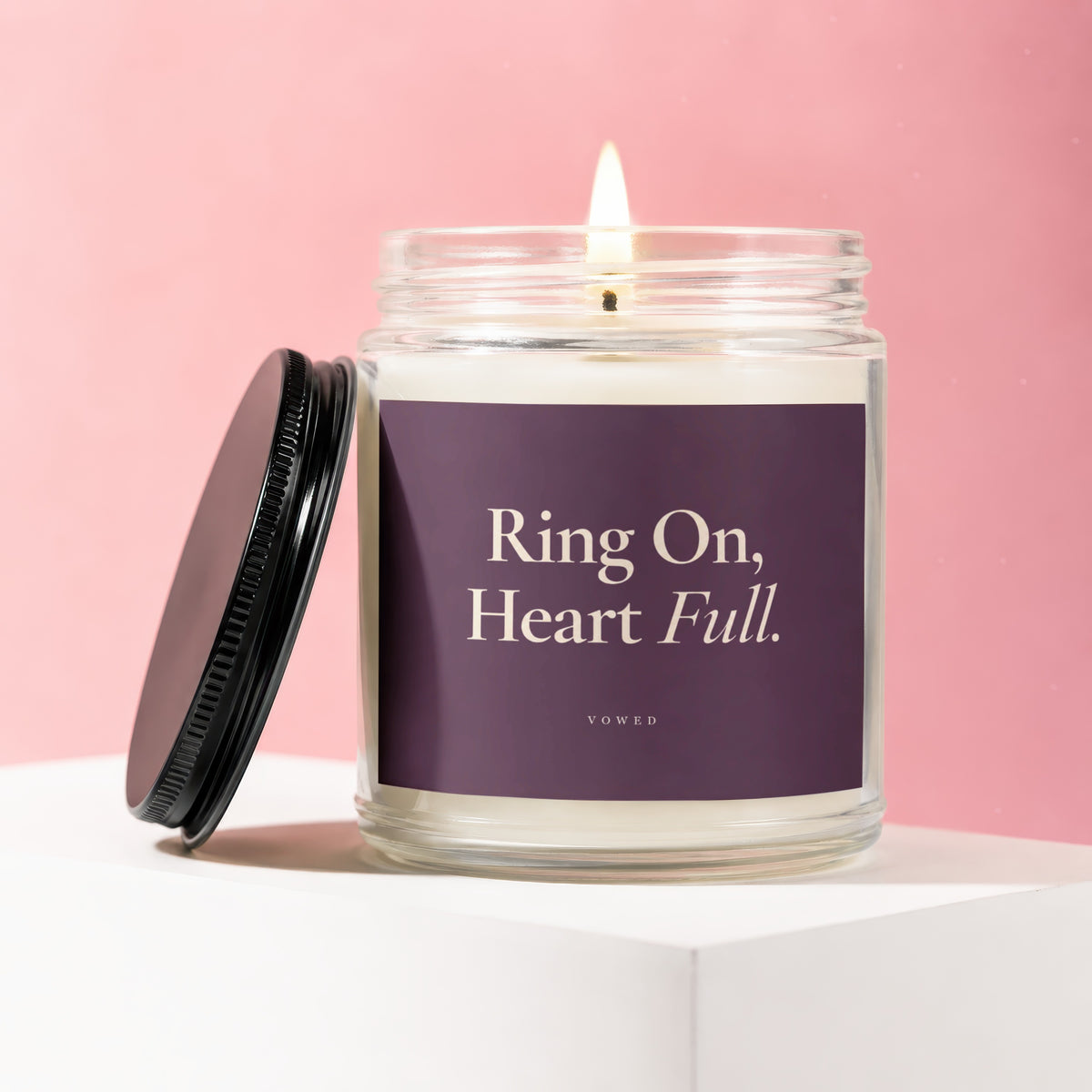 Lit candle in glass jar with lid off, reads "Ring On, Heart Full."