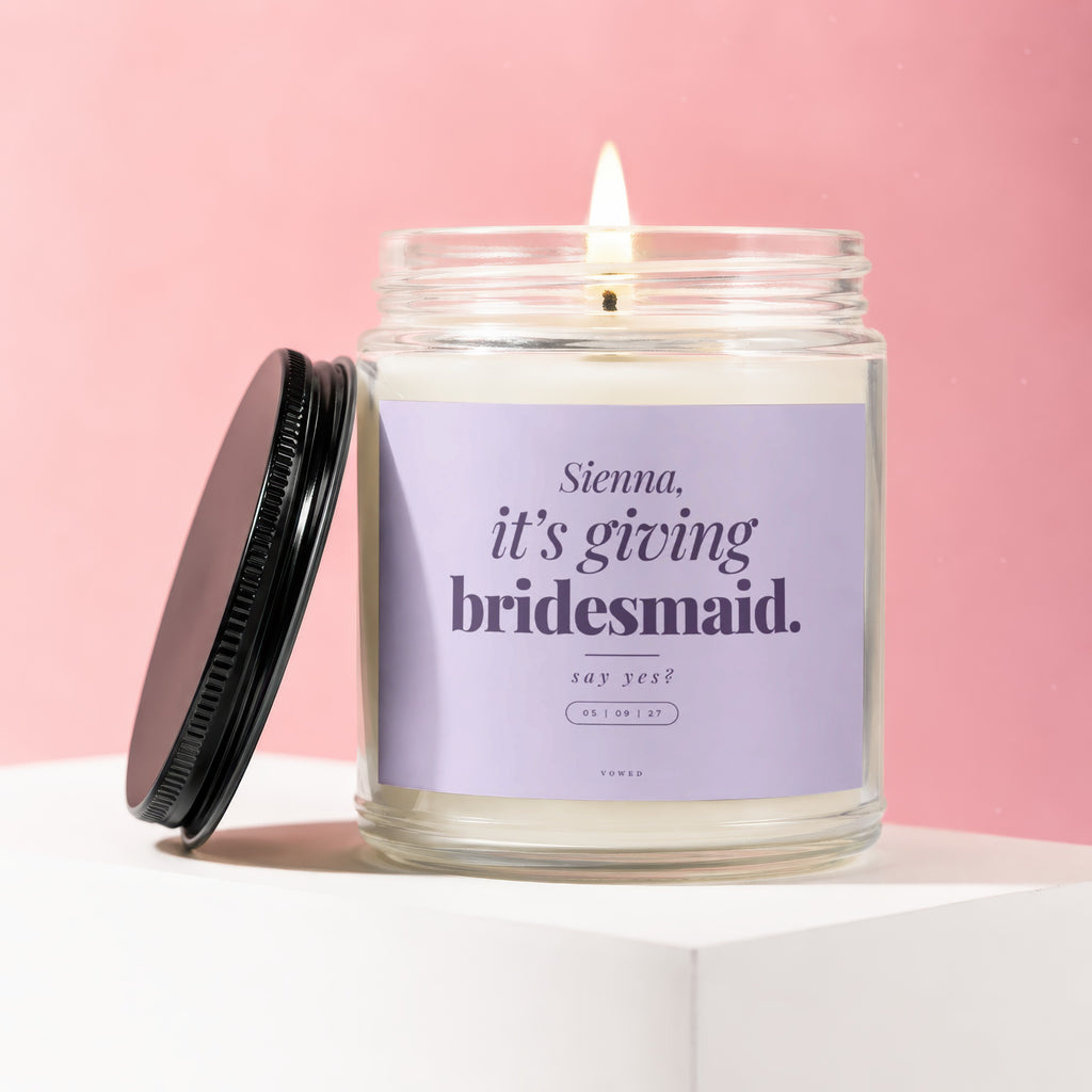 Candle with purple label reading "Sienna, it's giving bridesmaid. say yes?"