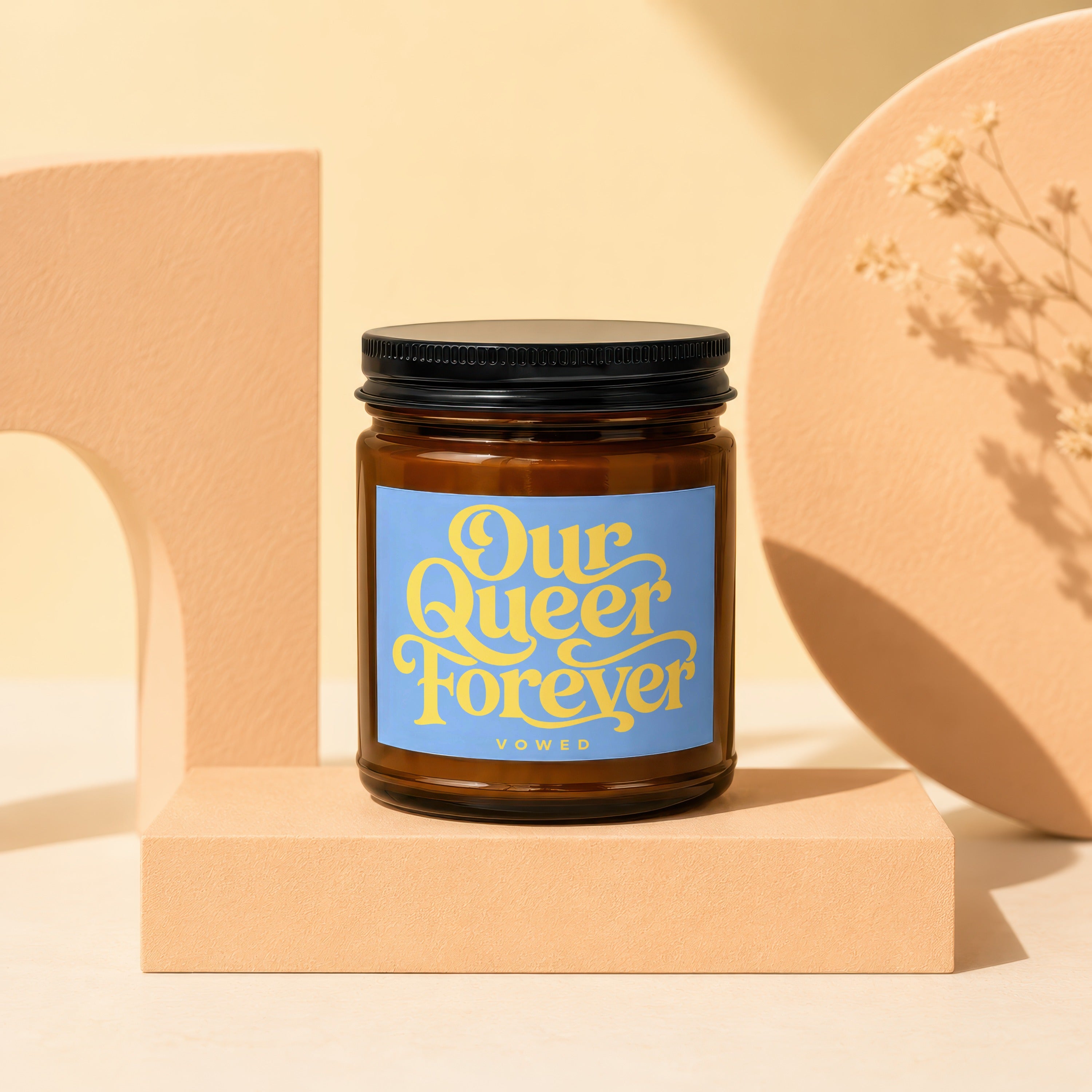 Candle with black lid and blue label reading "Our Queer Forever Vowed".