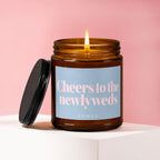Amber jar candle burning, with text "Cheers to the newlyweds" and "vowed" on label.