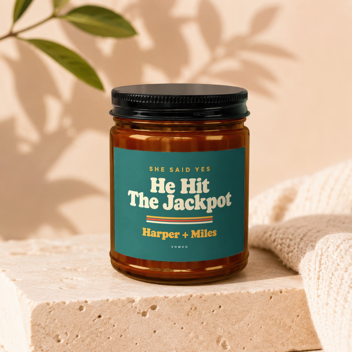Amber jar candle with "He Hit The Jackpot" and "Harper + Miles" text on teal label.