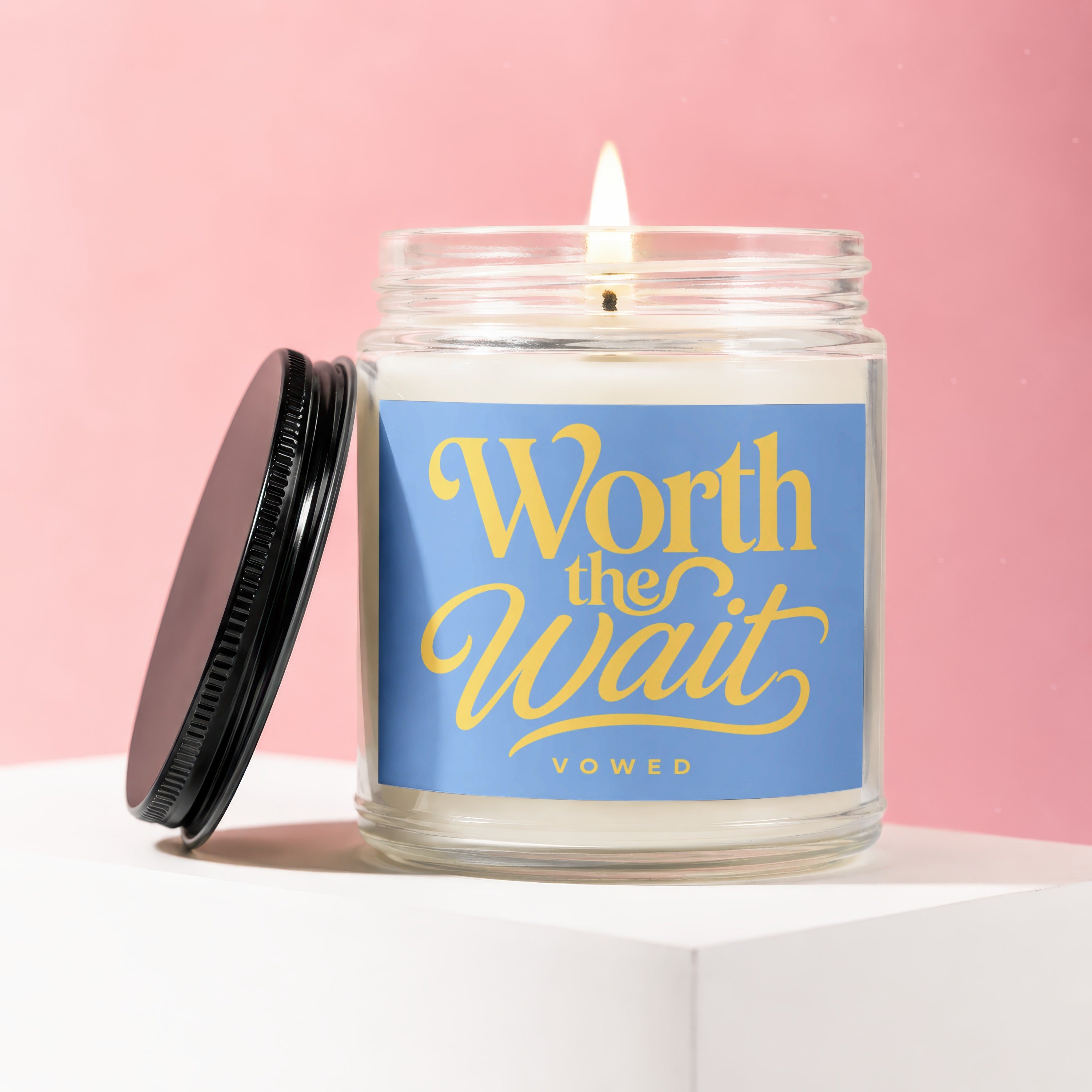 Candle with "Worth the Wait" on a blue label, lid removed.