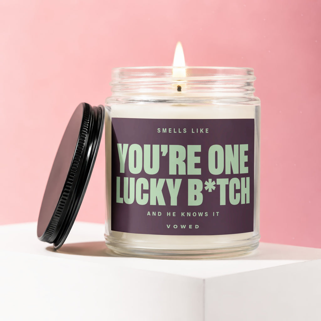 Candle with label reading "Smells like You're One Lucky B*tch. And He Knows It. Vowed."