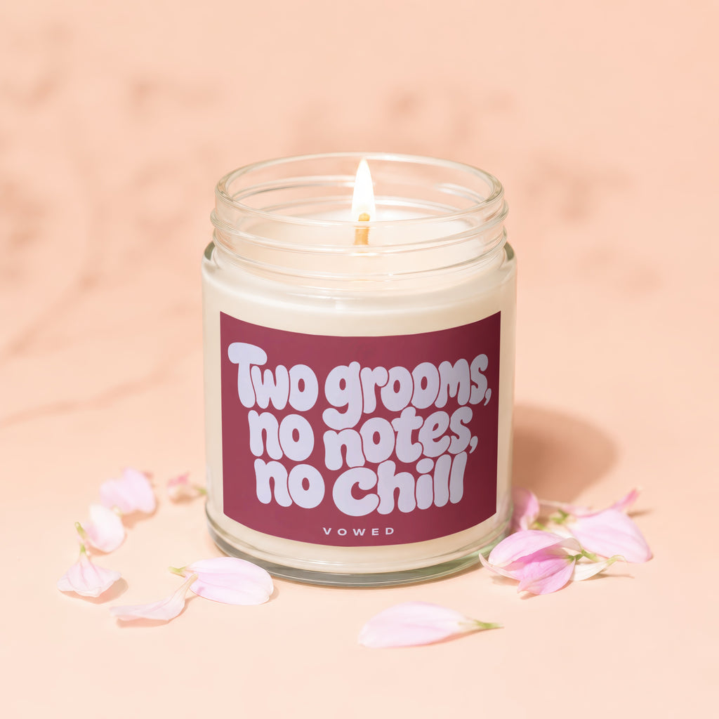 Candle with label "Two grooms, no notes, no chill" surrounded by pink petals.