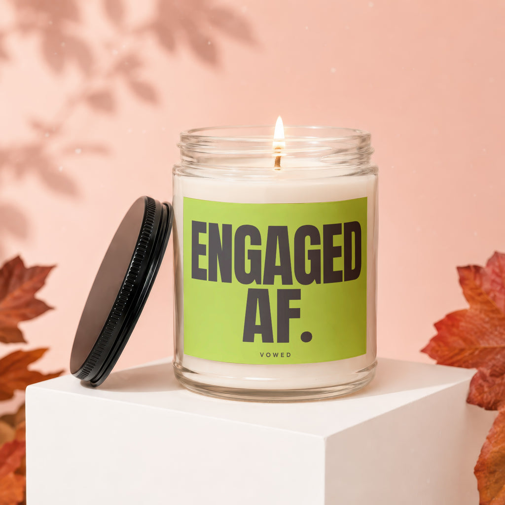 Glass candle with "ENGAGED AF. VOWED" text on a lime green label, lid off.