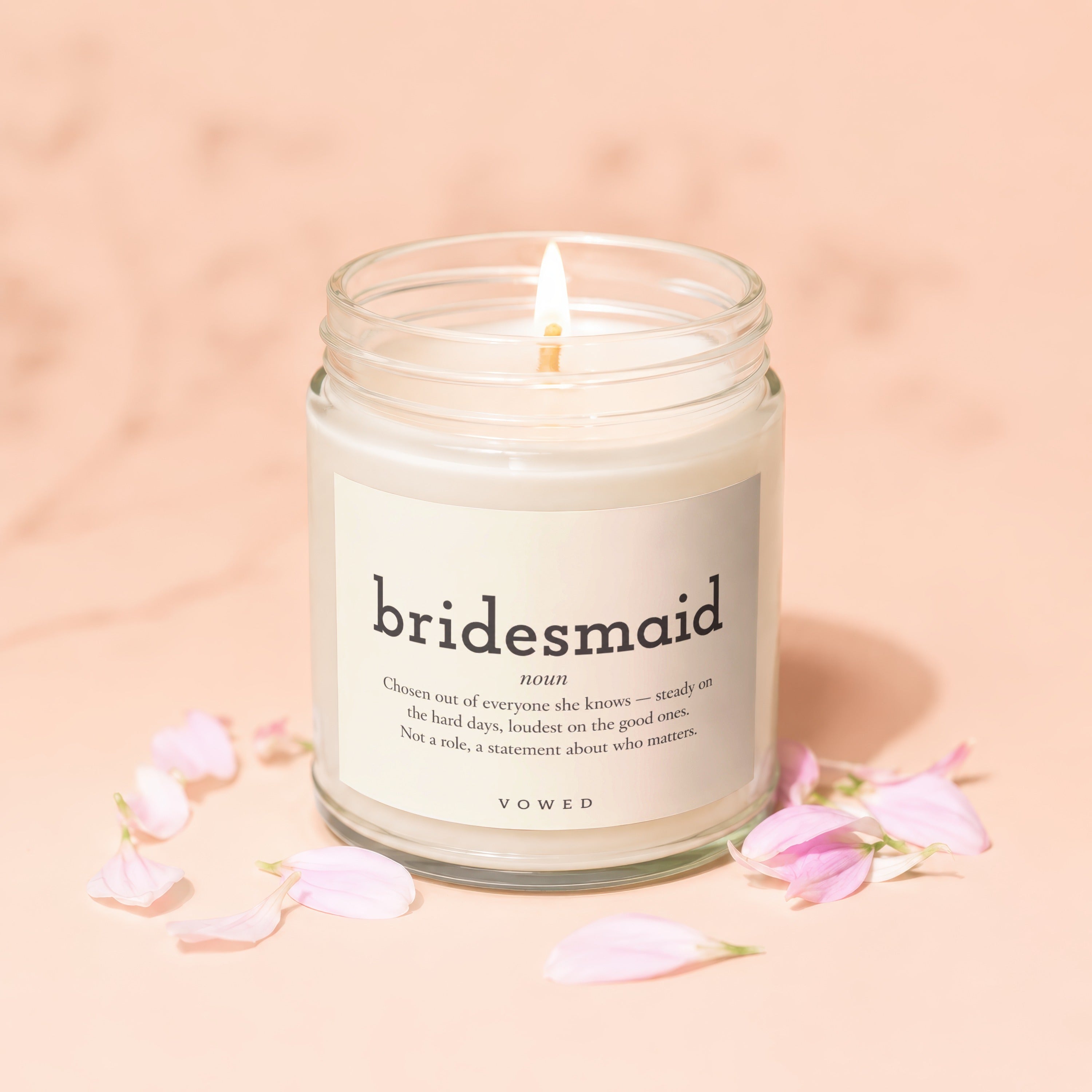 Candle with label reading "bridesmaid" and definition, surrounded by pink petals.
