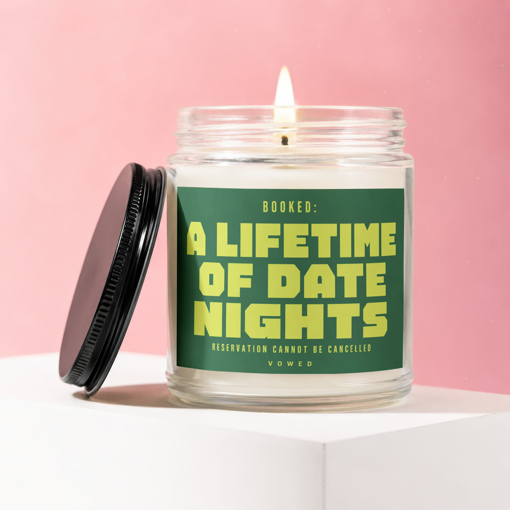 Glass jar candle with lid off, lit wick, and text "Booked: A Lifetime of Date Nights".