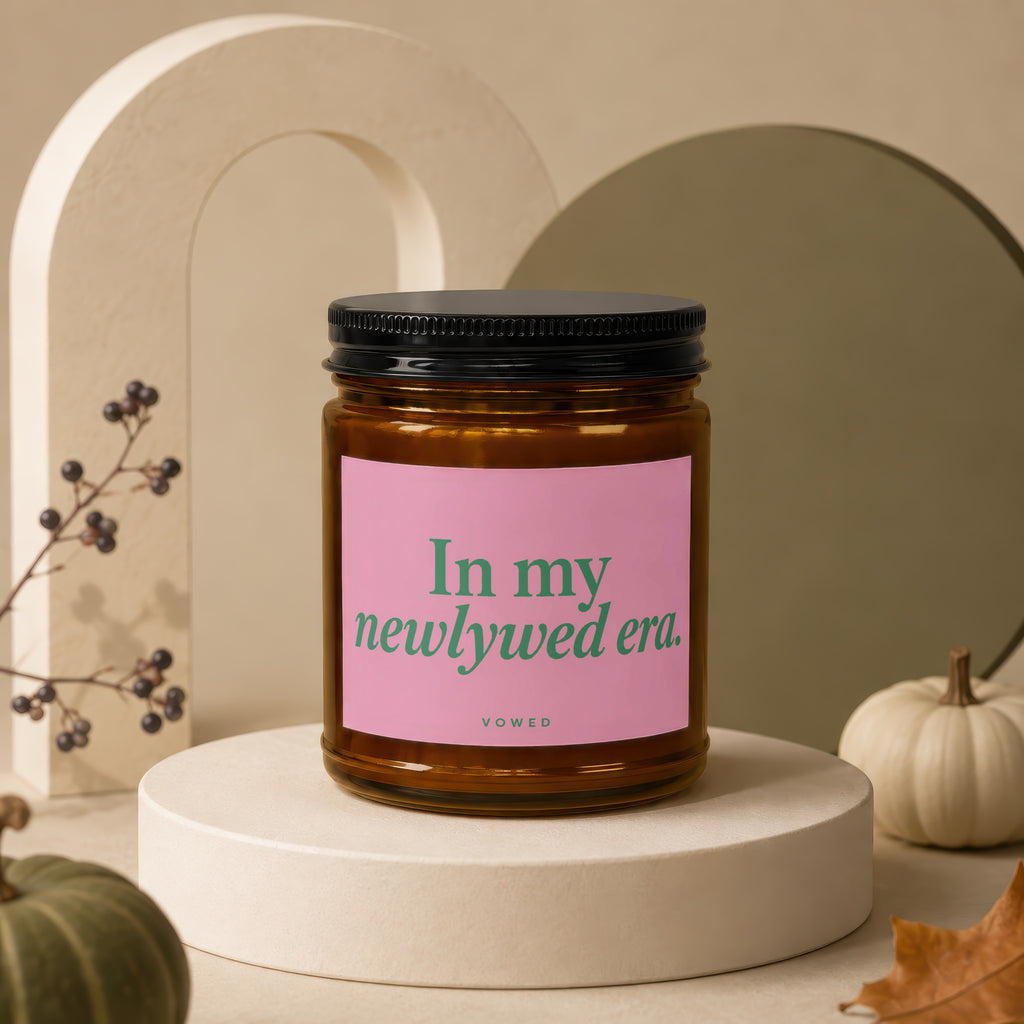 Glass candle with pink label reading "In my newlywed era. vowed".
