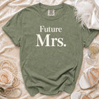 Olive green t-shirt with "Future Mrs." text, styled with pearls, a rose, and champagne.