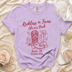 Lavender t-shirt with "Reckless in Texas Olivia's Bach Austin, TX Summer 2026" and desert graphics.