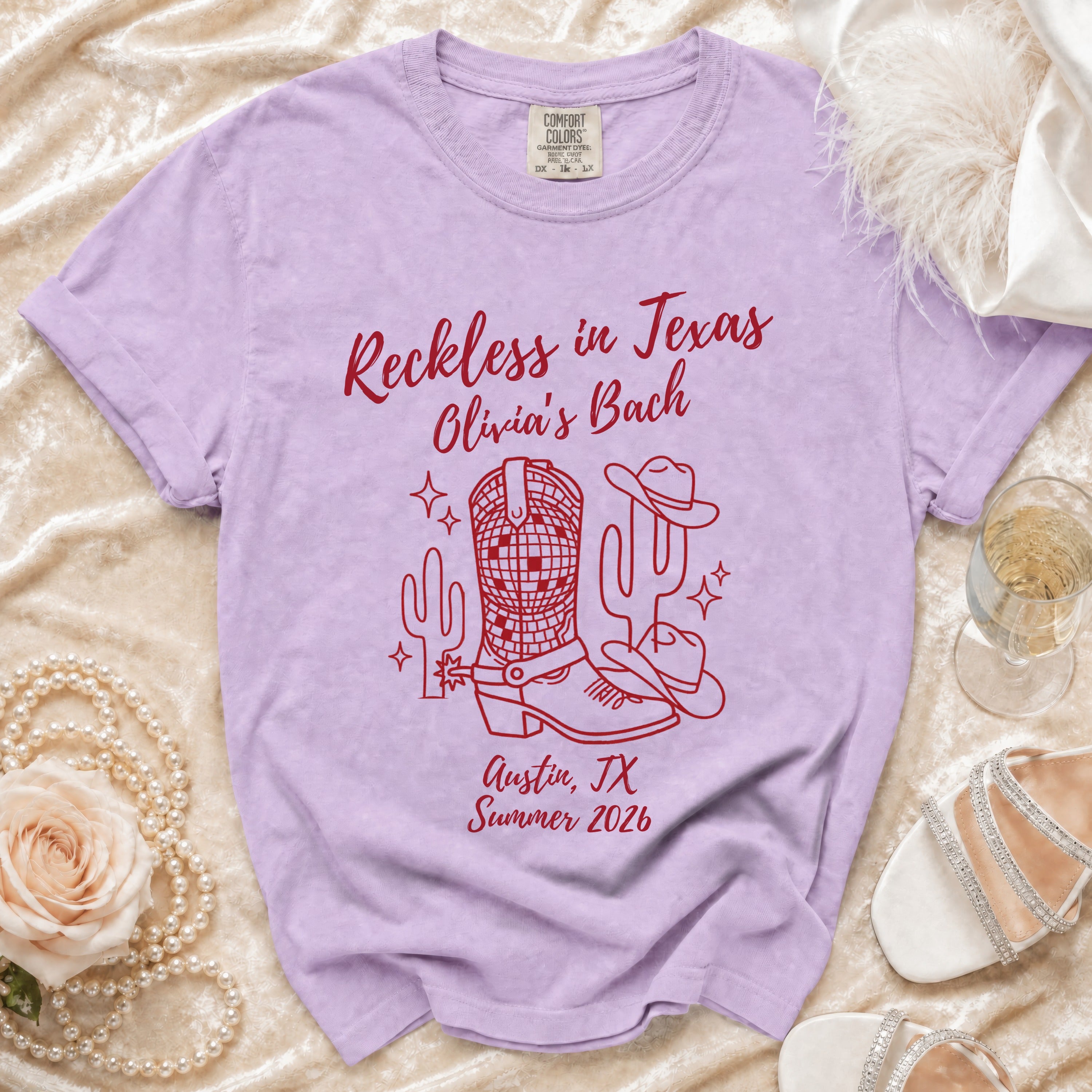 Lavender t-shirt with "Reckless in Texas Olivia's Bach Austin, TX Summer 2026" and desert graphics.
