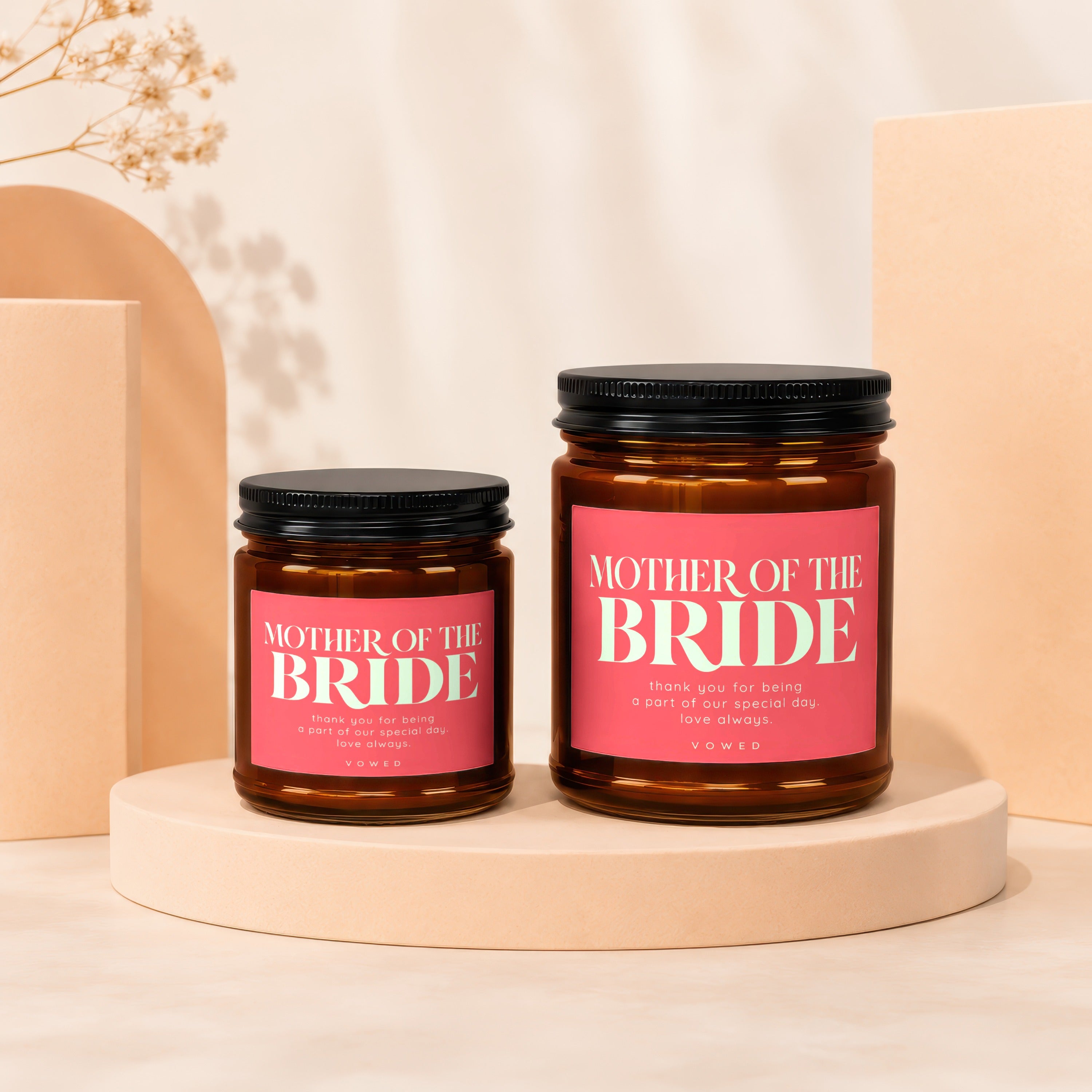 Two amber glass candles labeled "Mother of the Bride" with pink labels.