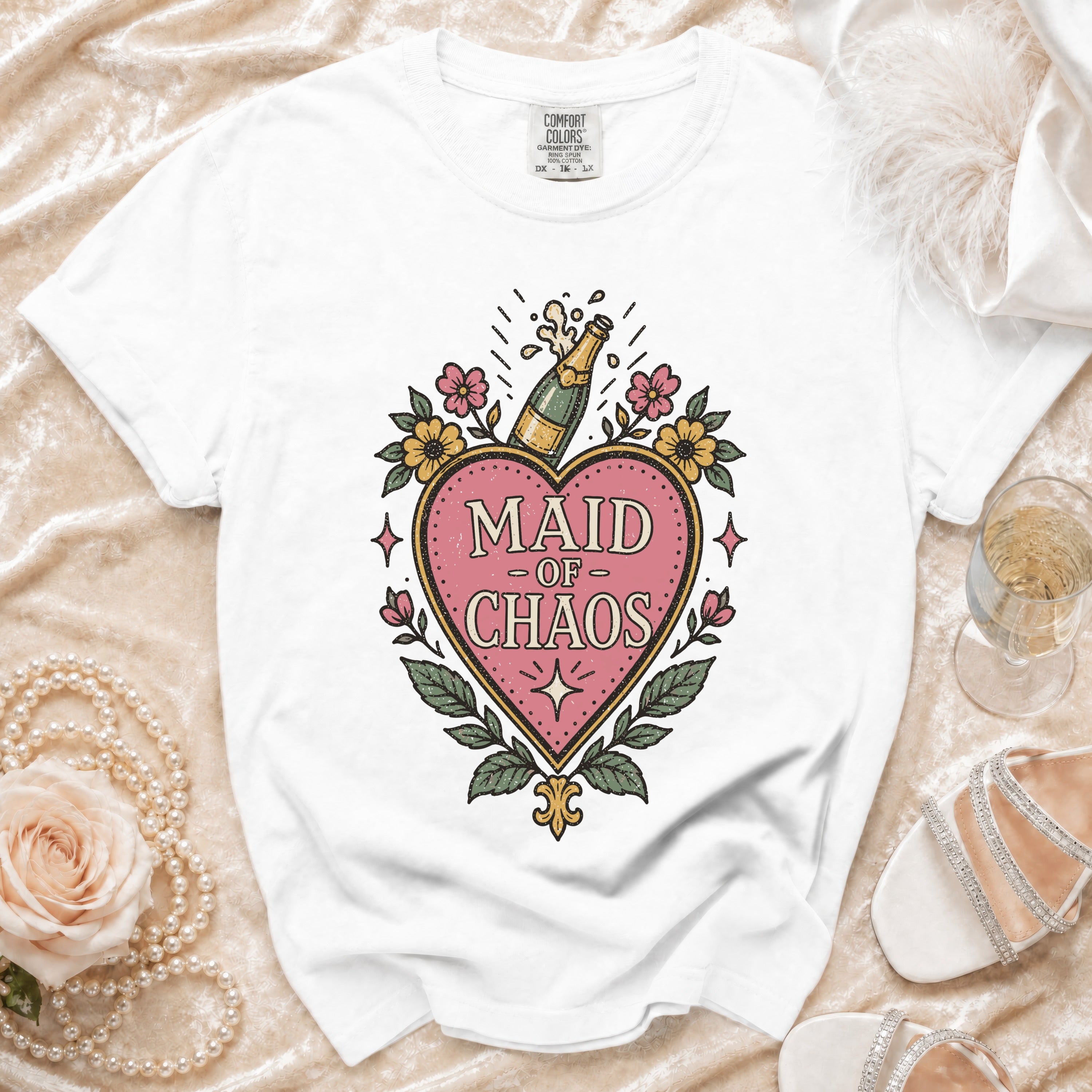 White t-shirt with "Maid of Chaos" text and champagne bottle graphic.