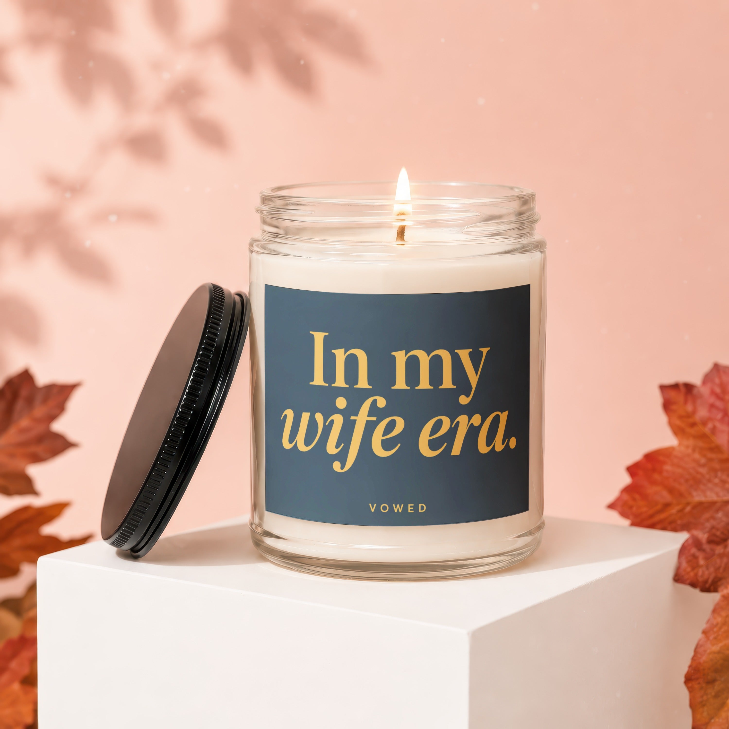 Lit candle in glass jar with "In my wife era." text by VOWED.