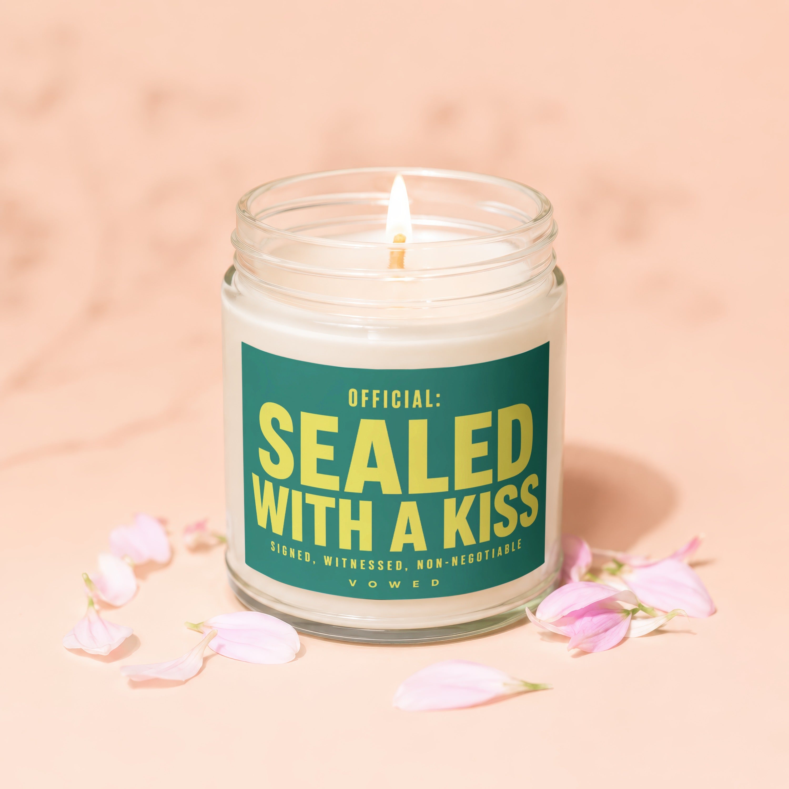 Jar candle with lit wick and label reading "OFFICIAL: SEALED WITH A KISS".
